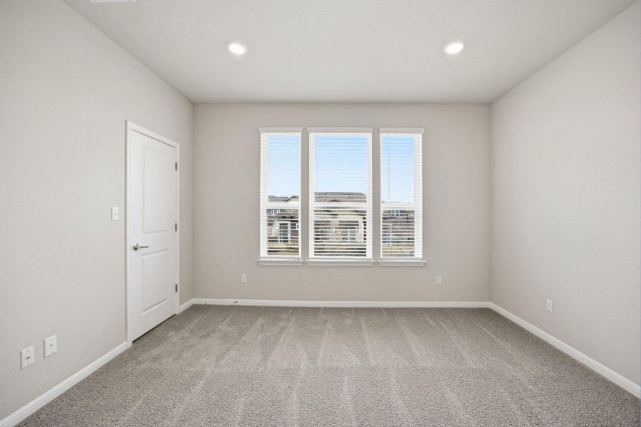Empty room with light colored carpet and recessed lighting
