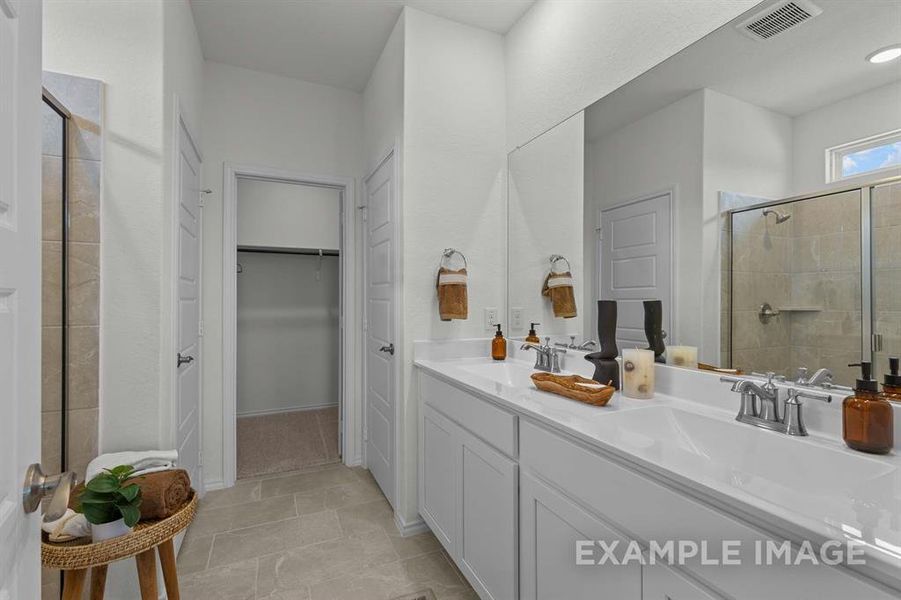 Bathroom featuring tile patterned floors, vanity, and a shower with door