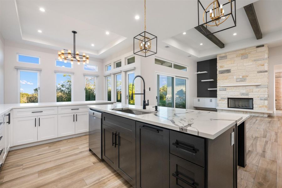 Kitchen featuring decorative light fixtures, sink, stainless steel dishwasher, and a center island with sink