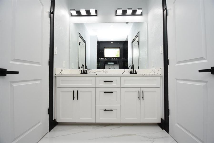 This bathroom, with its bathtub and shower combination, features beautiful finishes, two sinks, and serves two adjacent rooms.