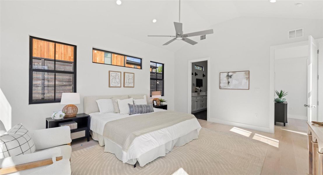 Bedroom with ensuite bathroom, vaulted ceiling, light wood-style flooring, ceiling fan, and recessed lighting