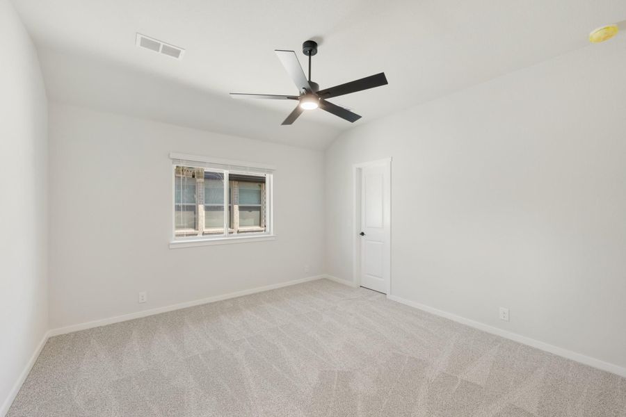 Empty bedroom with vaulted ceiling, black ceiling fan, carpet flooring, and a single window