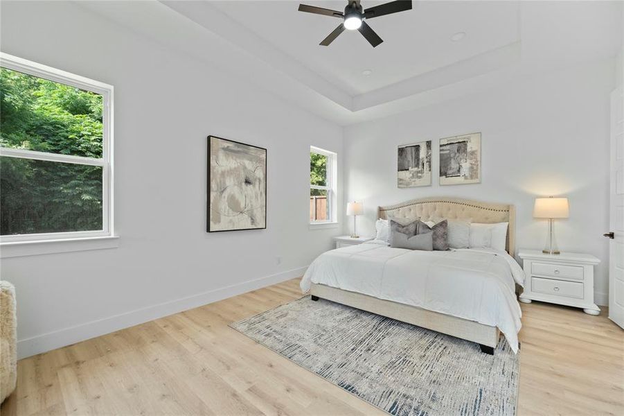 Bedroom featuring light wood-type flooring, a tray ceiling, and ceiling fan Bedroom featuring light wood-type flooring, a tray ceiling, and ceiling fan