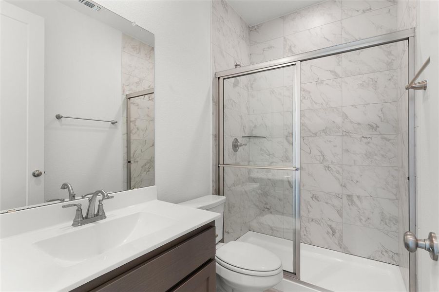 Full bath with toilet, a stall shower, and vanity