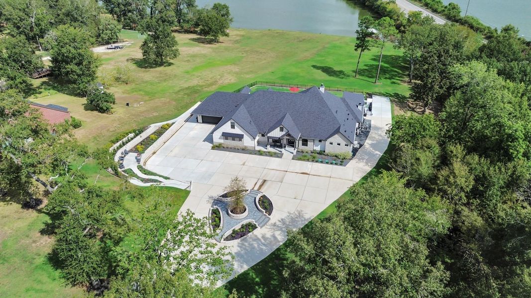 Stunning estate with a sprawling driveway and lush landscaping, nestled by a serene lake, offering privacy and picturesque views.