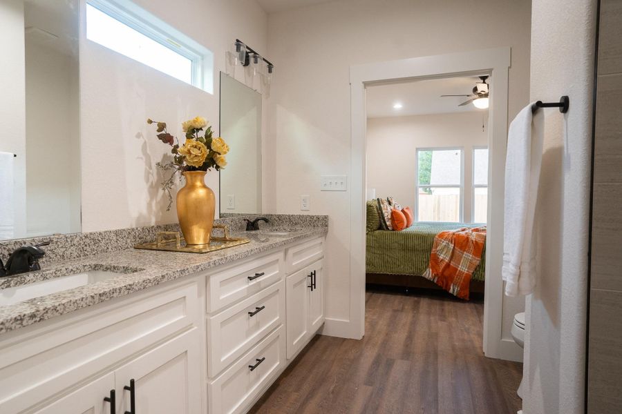 Full bathroom with wood finished floors, double vanity, toilet, a ceiling fan, and connected bathroom