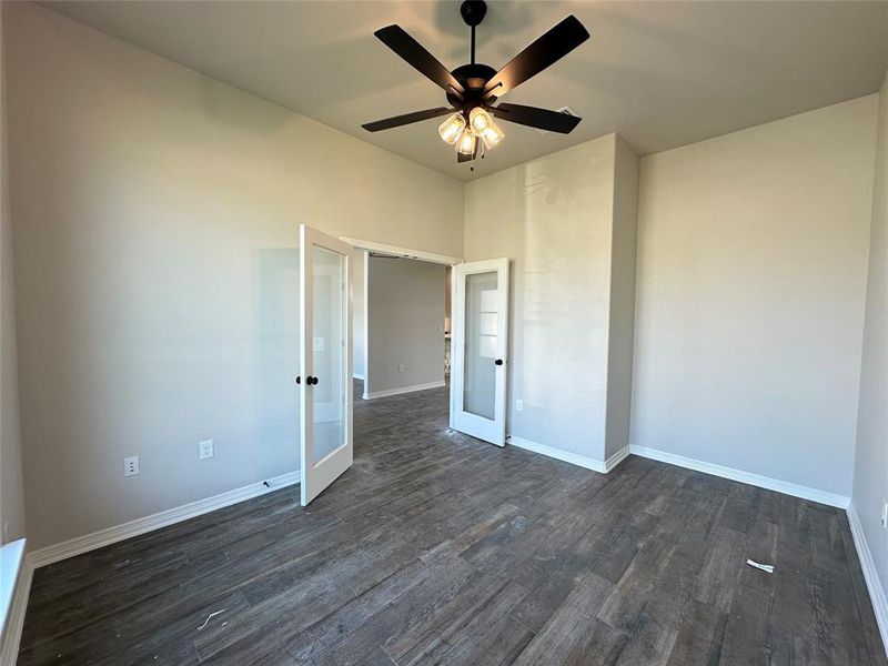Unfurnished bedroom with french doors, dark wood-style floors, and a ceiling fan Unfurnished bedroom with french doors, dark wood-style floors, and a ceiling fan