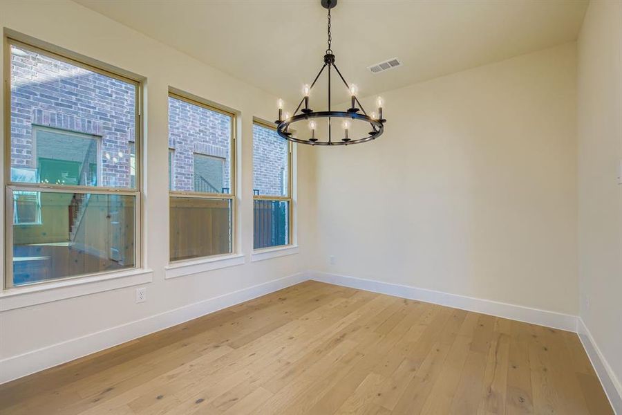 Unfurnished dining area featuring light wood finished floors and a chandelier