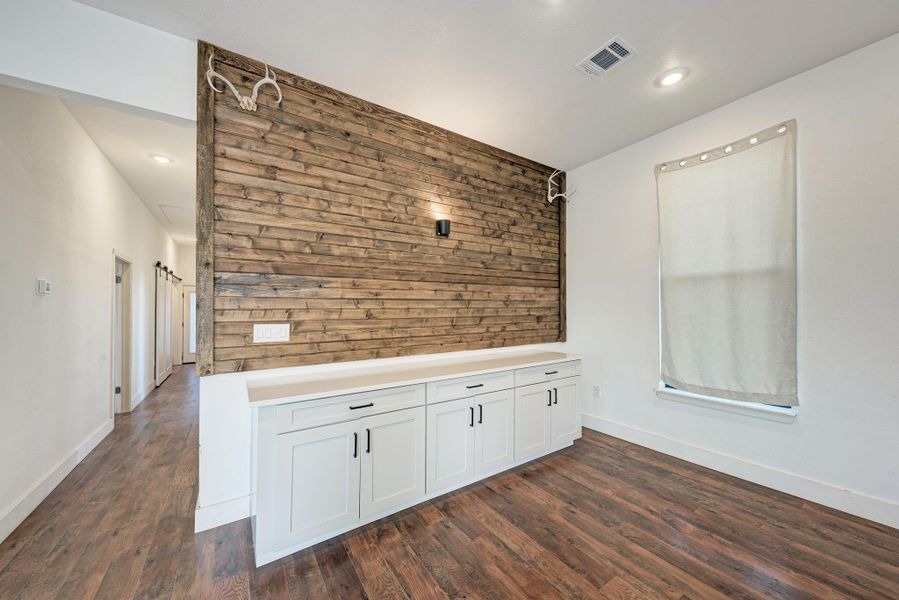 Rich wood floors complement a textured accent wall and built-in cabinetry in this open entryway.