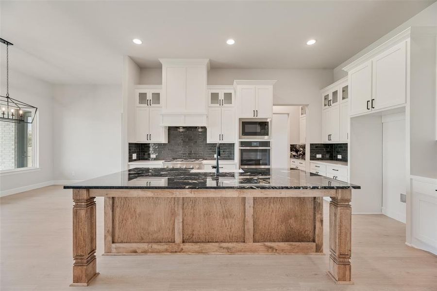 Kitchen with glass insert cabinets, backsplash, oven, white cabinets, and recessed lighting