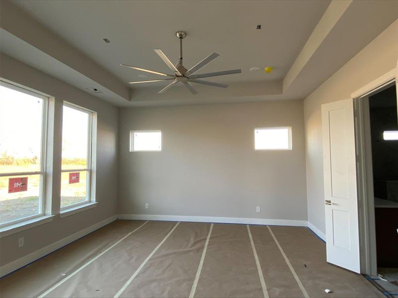 Spare room featuring a raised ceiling, a ceiling fan, and healthy amount of natural light Spare room featuring a raised ceiling, a ceiling fan, and healthy amount of natural light