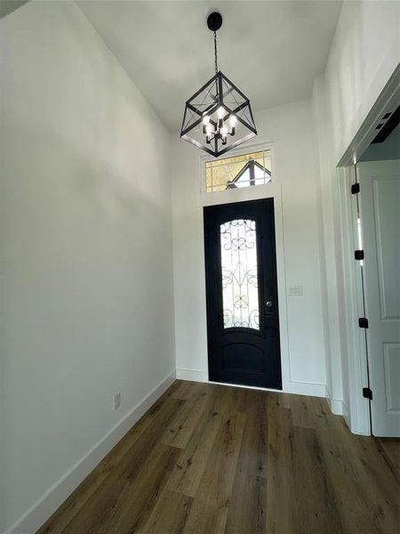 Foyer featuring wood finished floors and a chandelier Foyer featuring wood finished floors and a chandelier