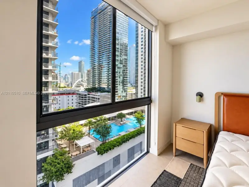 Floor-to-ceiling windows featuring black framing and motorized roller shades, showcasing expansive metropolitan scenery Floor-to-ceiling windows featuring black framing and motorized roller shades, showcasing expansive metropolitan scenery