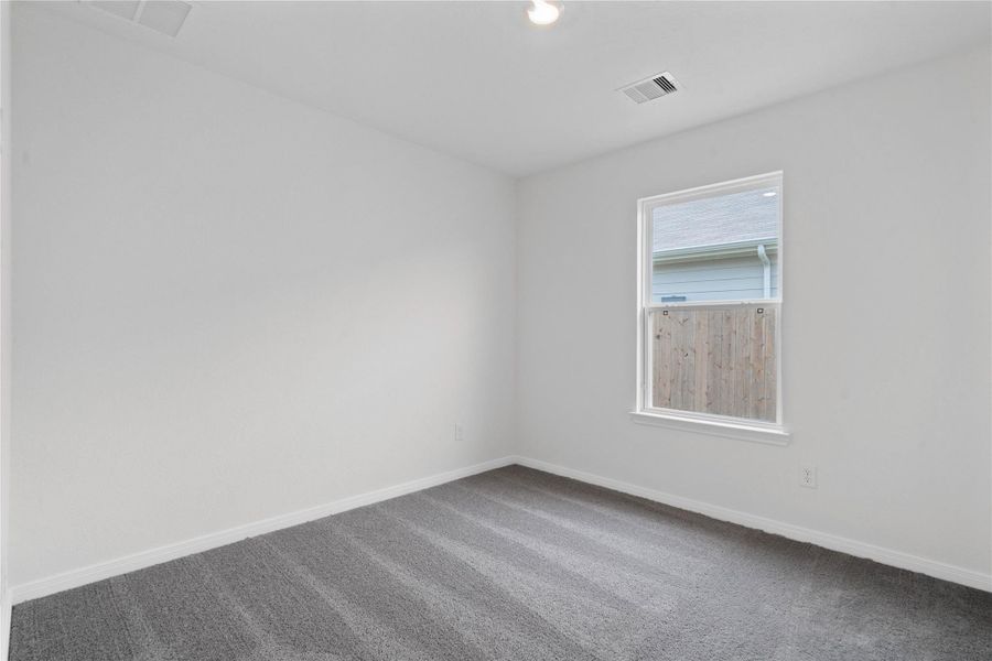 This secondary bedroom combines comfort and style, featuring plush carpeting, neutral paint, a large window, and a spacious closet.