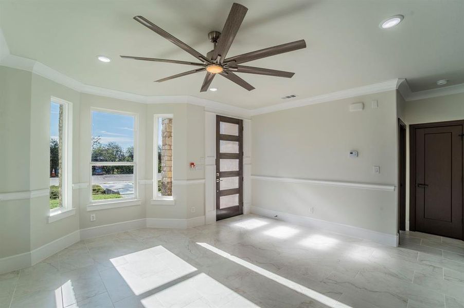 Unfurnished room with light marble finish flooring, ornamental molding, a ceiling fan, and recessed lighting Unfurnished room with light marble finish flooring, ornamental molding, a ceiling fan, and recessed lighting
