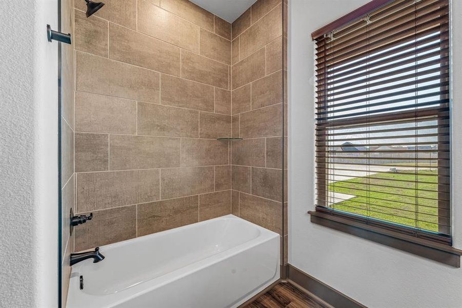 Bathroom with bathtub / shower combination, plenty of natural light, and dark wood-type flooring