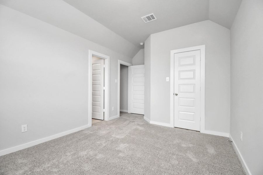 Secondary bedroom features plush carpeting, large windows that let in plenty of natural light, bright paint, and spacious closets. Sample photo of completed home with similar floor plan. Actual colors and selections may vary.