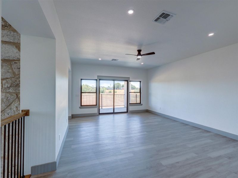 Sliding glass doors open to a balcony, framing views of the rolling hills beyond.