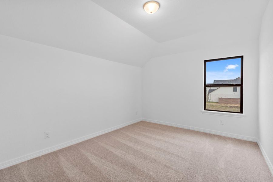 An inviting secondary bedroom that balances refined finishes with everyday livability with plush carpet and a well placed window.