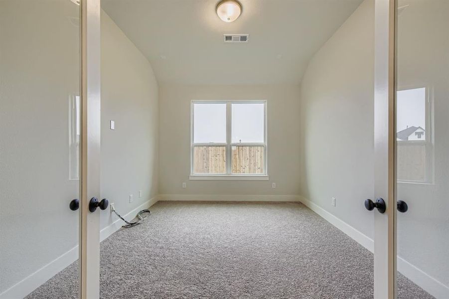Unfurnished room featuring light colored carpet and vaulted ceiling
