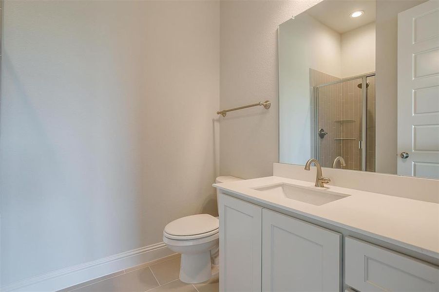 Bathroom featuring tile patterned flooring, toilet, a shower with shower door, and vanity