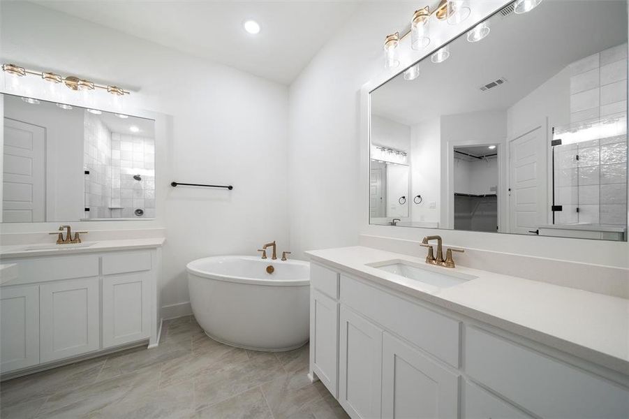 Bathroom with two vanities, a tile shower, a soaking tub, recessed lighting, and a walk in closet