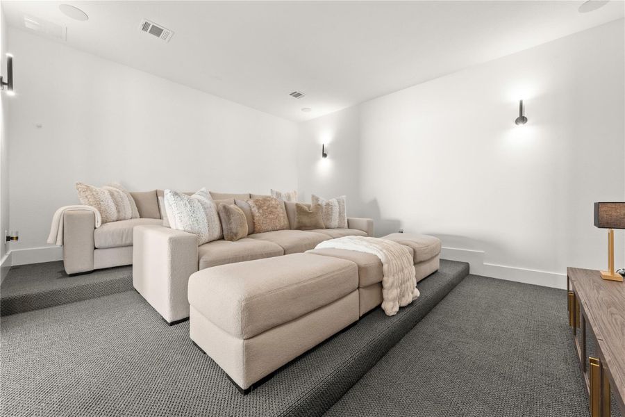 Movie room off of game room hosts surround sound and sconce lighting.