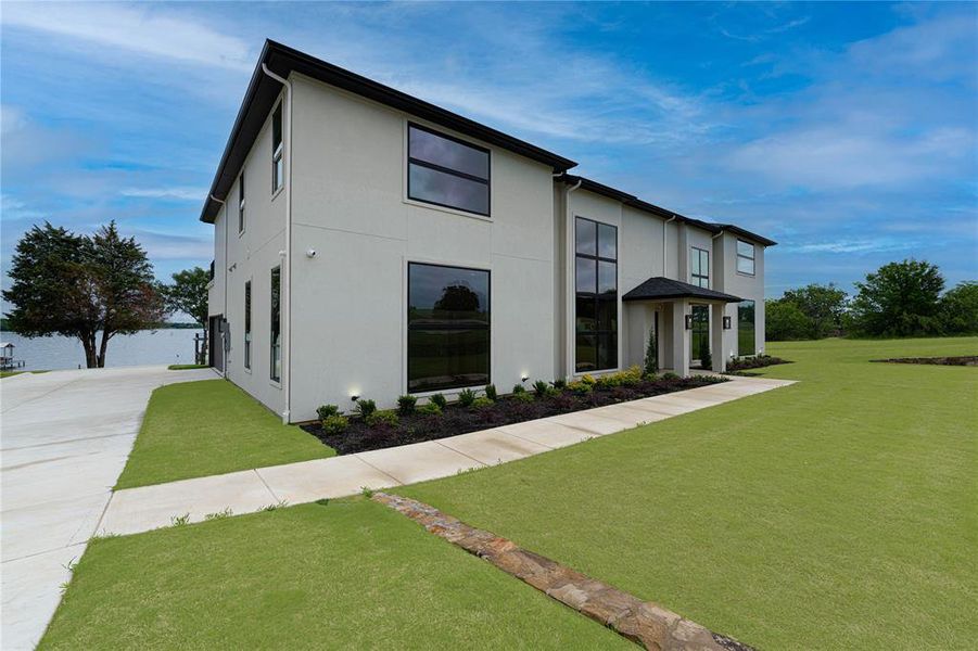 Contemporary home featuring stucco siding, a front lawn, and concrete driveway Contemporary home featuring stucco siding, a front lawn, and concrete driveway