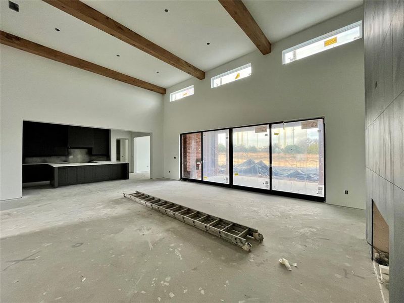 Unfurnished living room featuring beam ceiling and a high ceiling