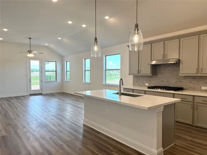 Kitchen featuring a sink, gray cabinetry, lofted ceiling, stainless steel gas stovetop, and healthy amount of natural light Kitchen featuring a sink, gray cabinetry, lofted ceiling, stainless steel gas stovetop, and healthy amount of natural light