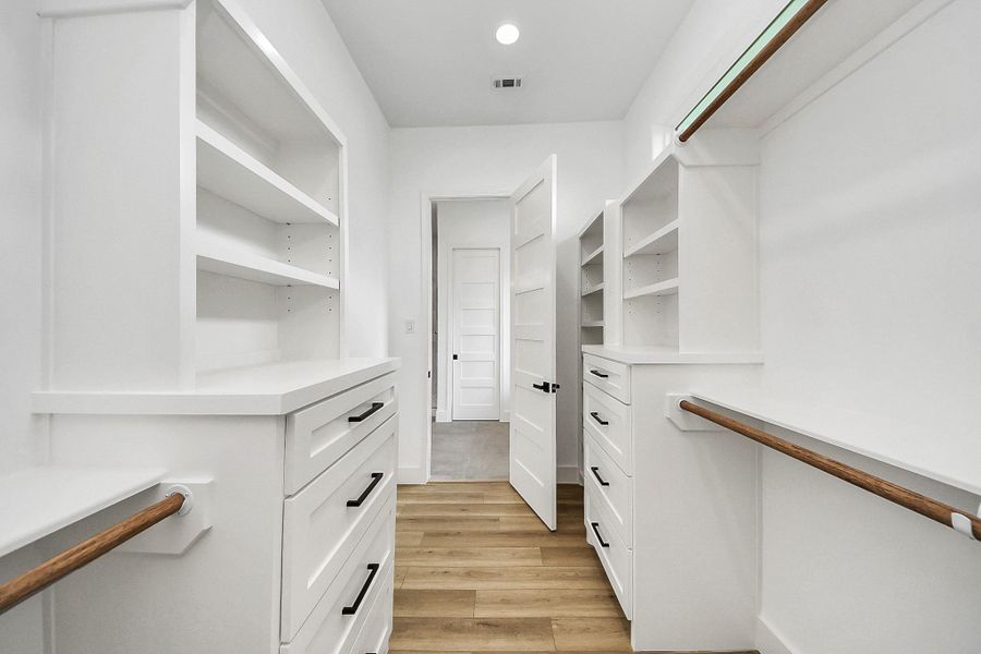 Spacious primary walk-in closet featuring custom built-in shelving and drawers, offering plenty of room for organized storage. Thoughtfully designed layout provides both functionality and ease for everyday living.