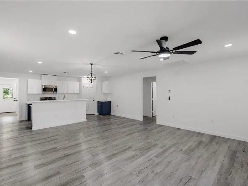 Unfurnished living room featuring recessed lighting, light wood-style flooring, a chandelier, and ceiling fan