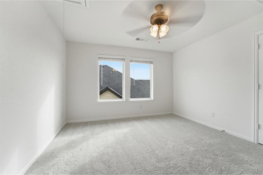 Room featuring light gray carpeting, neutral white walls, two windows with blinds, a ceiling fan with integrated lighting, and white baseboards