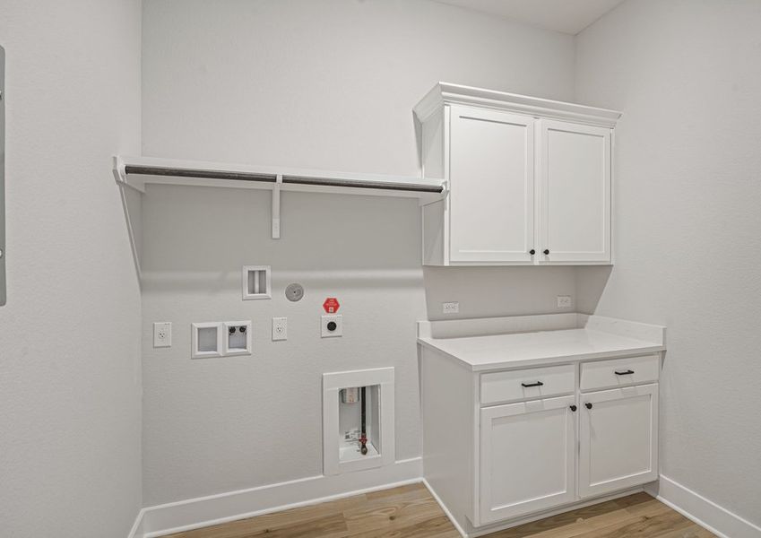 The laundry room has a hanging space and cabinets with a counter. The laundry room has a hanging space and cabinets with a counter.