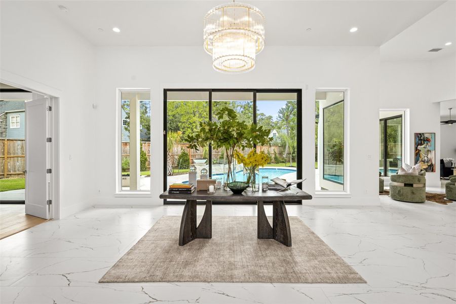 Entering through grand double iron and glass doors, you're welcomed into a spacious foyer with soaring 13-foot ceilings. Expansive floor-to-ceiling sliding glass doors showcase the sparkling pool beyond, while a striking three-tiered gold and crystal chandelier brings a modern touch of glamour. Entering through grand double iron and glass doors, you're welcomed into a spacious foyer with soaring 13-foot ceilings. Expansive floor-to-ceiling sliding glass doors showcase the sparkling pool beyond, while a striking three-tiered gold and crystal chandelier brings a modern touch of glamour.