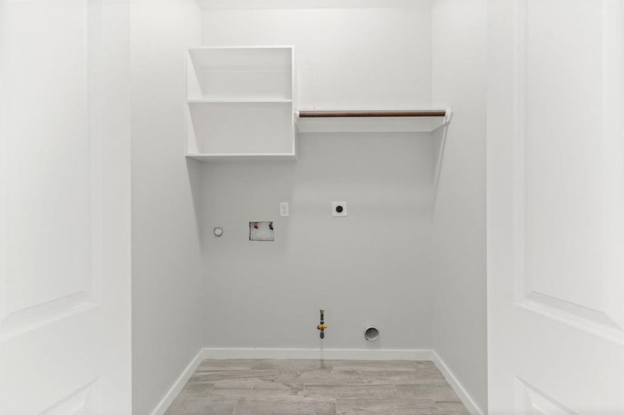 Clean laundry area prepped for appliance installation, featuring a white cabinet, hanging rod, and hookups for a washer and dryer.