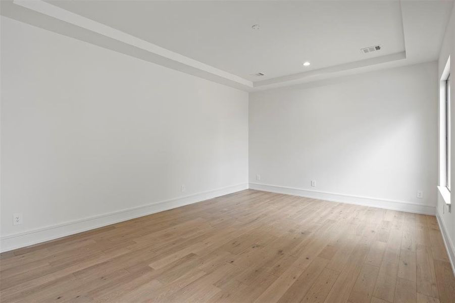 Empty room featuring a raised ceiling, light wood-style flooring, and recessed lighting Empty room featuring a raised ceiling, light wood-style flooring, and recessed lighting