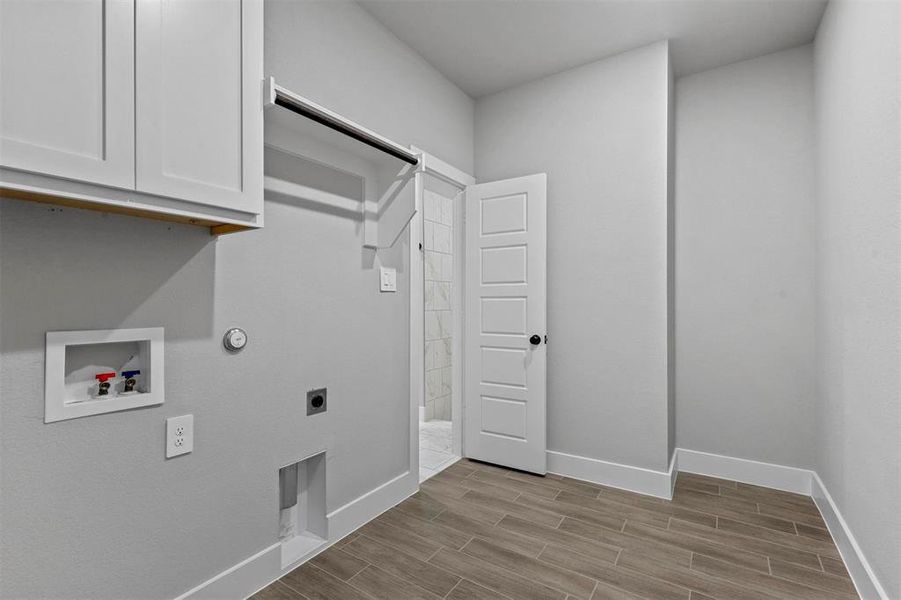 Clothes washing area with electric dryer hookup, cabinets, hookup for a gas dryer, light hardwood / wood-style flooring, and hookup for a washing machine