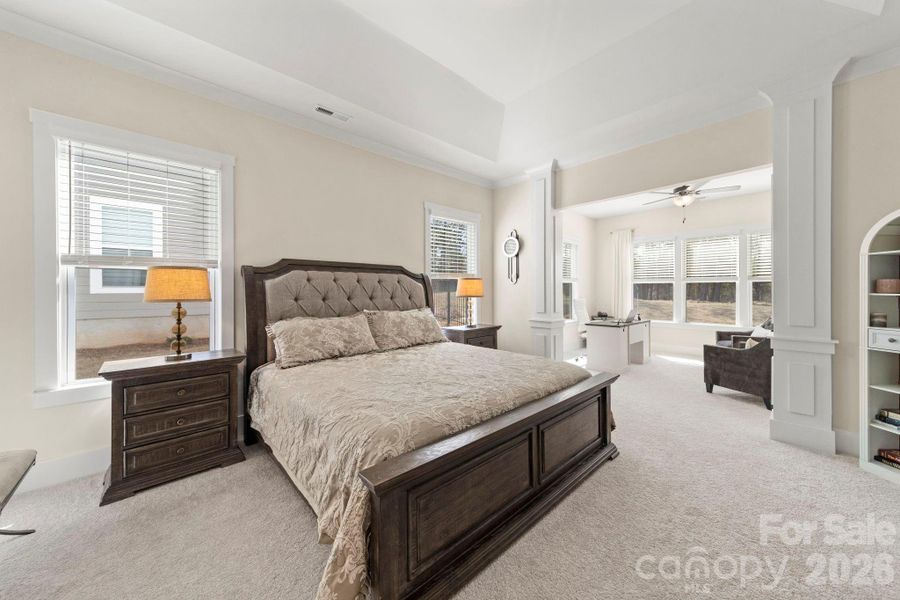 Primary Bedroom with Tray Ceiling and view of Sitting Room and Columns