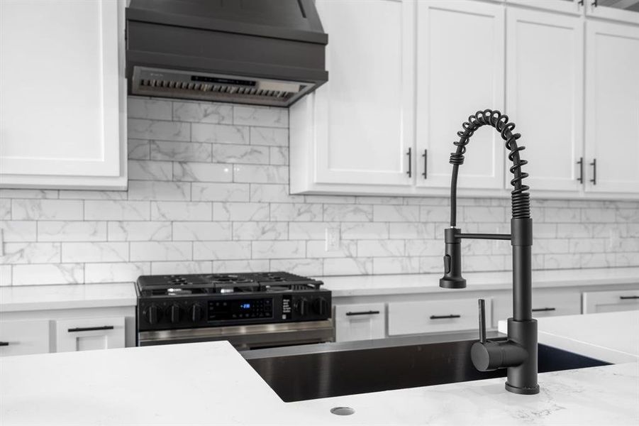 Kitchen featuring tasteful backsplash, white cabinets, light stone countertops, and wall chimney exhaust hood