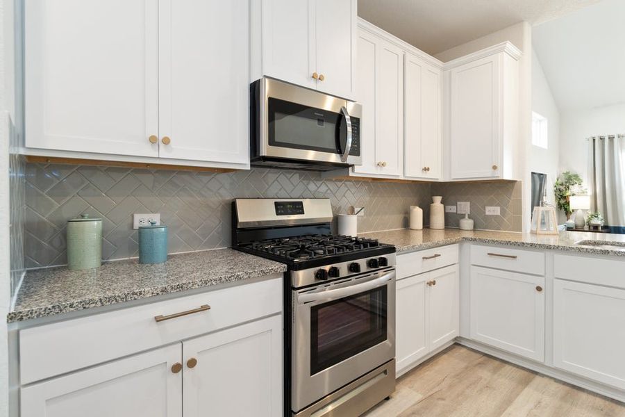 White kitchen with granite countertops, stainless steel appliances, and herringbone tile backsplash White kitchen with granite countertops, stainless steel appliances, and herringbone tile backsplash
