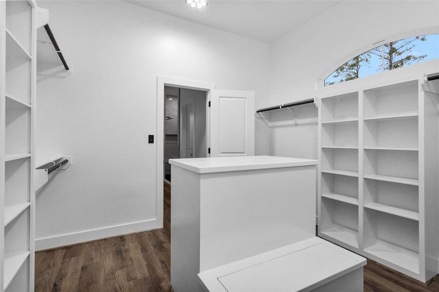 This is a reverse view of the closet showing a bench with storage and additional hanging space.