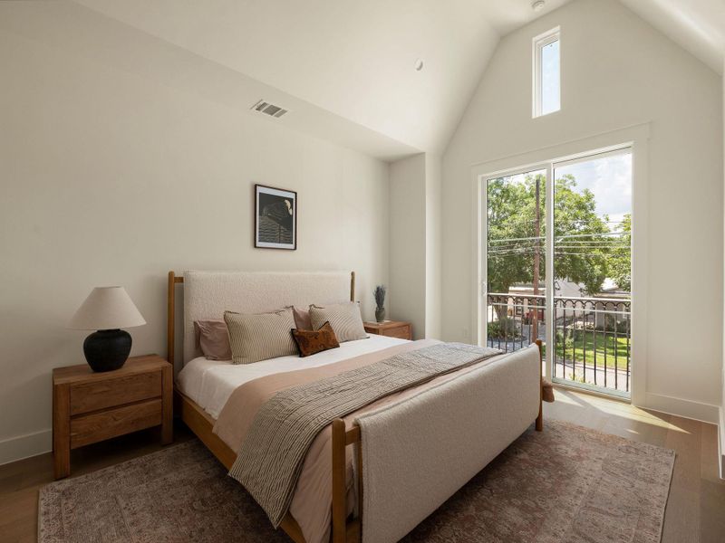 Natural light streams into this bedroom through a sliding glass door and high arched window.
