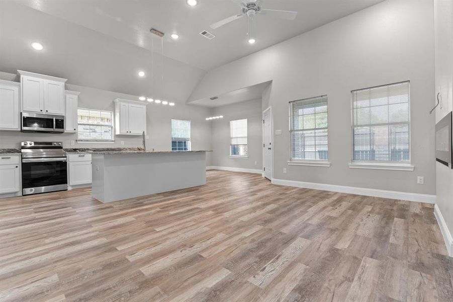 Kitchen with appliances with stainless steel finishes, open floor plan, white cabinetry, light wood-type flooring, and recessed lighting Kitchen with appliances with stainless steel finishes, open floor plan, white cabinetry, light wood-type flooring, and recessed lighting