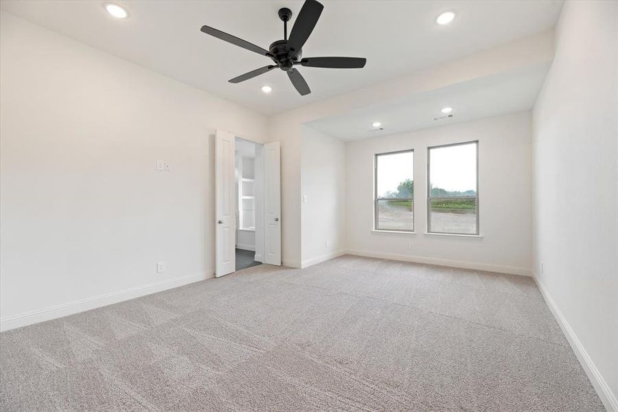 Unfurnished bedroom with ceiling fan and light colored carpet