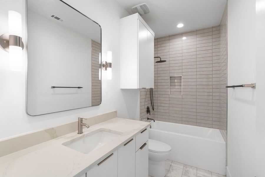 A well-appointed bathroom features a modern vanity and a tiled shower-tub combination.