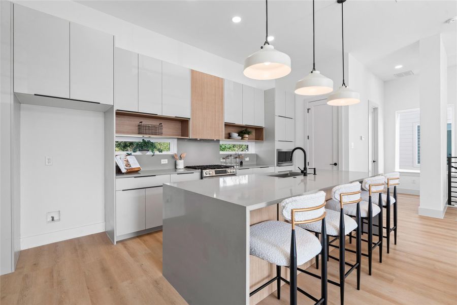 A tailored cabinet layout with open display shelving anchors the kitchen, while pendant lighting illuminates an island designed to comfortably seat four. A tailored cabinet layout with open display shelving anchors the kitchen, while pendant lighting illuminates an island designed to comfortably seat four.