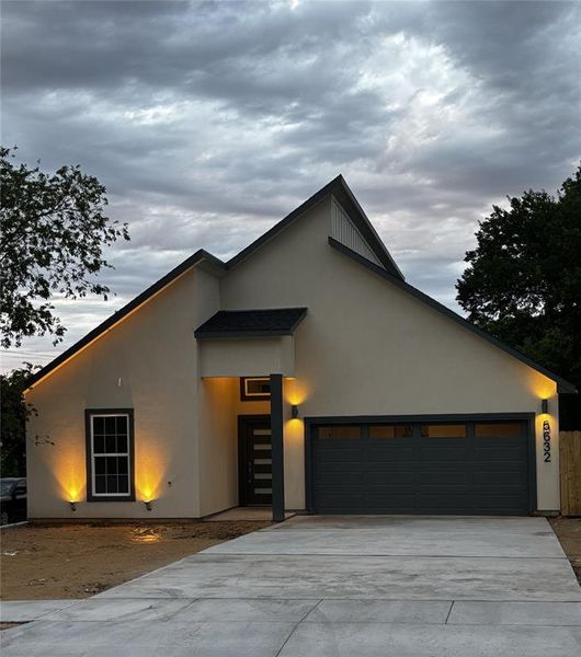Modern home with a garage, stucco siding, and concrete driveway