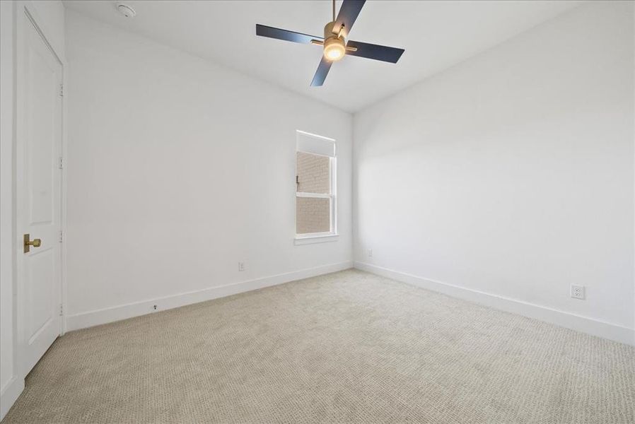 Carpeted spare room with a ceiling fan and baseboards