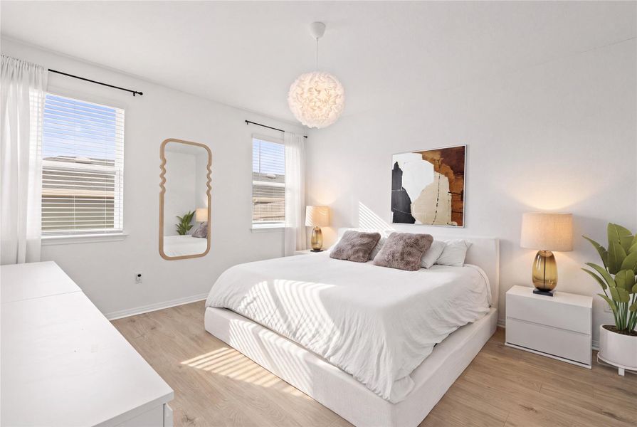 Sun-filled bedroom featuring light wood flooring and ample natural light through large windows.